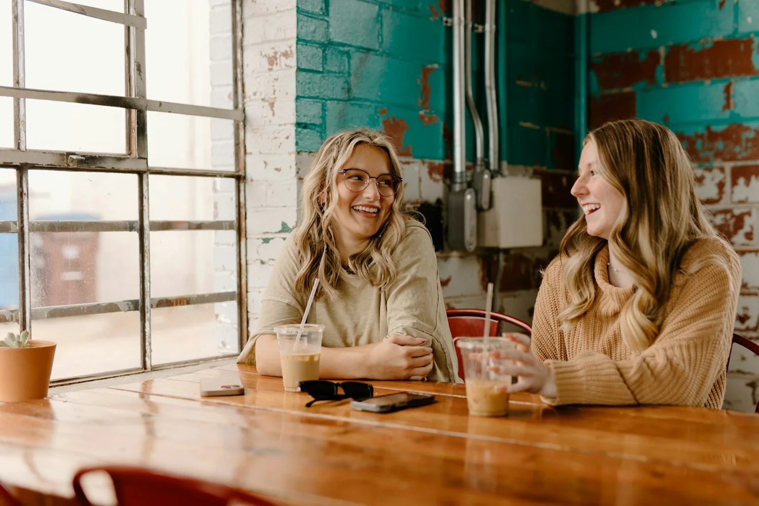 Deux personnes échangent avec le sourire dans un café lumineux.